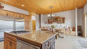 Une cuisine dotée de plans de travail en granit, d’appareils électroménagers en acier inoxydable, d’armoires en bois et d’un pare-feu en pierre.