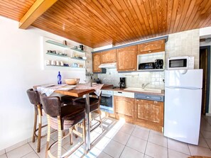 A kitchen with wooden cabinets, a white refrigerator, a microwave, a coffee maker, and a dining table with chairs. - Apartment - Le Chaniski - Valloire - 4 guests (Valloire)