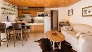 Una sala de estar acogedora con un sofá, una mesa de centro de madera, un comedor con sillas y una mesa, y una cocina con armarios de madera y electrodomésticos.