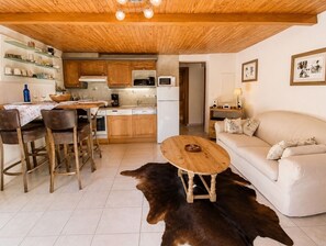 A cozy living room with a sofa, a wooden coffee table, a dining area with chairs and a table, and a kitchen with wooden cabinets and appliances. - Apartment - Le Chaniski - Valloire - 4 guests (Valloire)