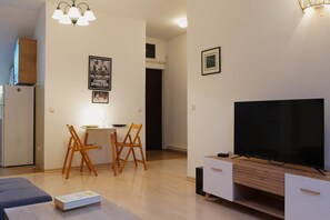 A compact living space with a dining area, a TV, and a kitchenette. - Stylish 1-Bedroom Apartment in Vračar Near Saint Sava Temple (Beograd)