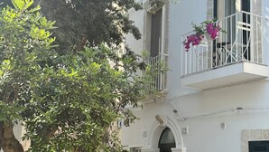 A building with a balcony, a potted tree, and a stone wall. - Angel Apartment 1 - Two Bedroom Apartment, Sleeps 4 (Monopoli)