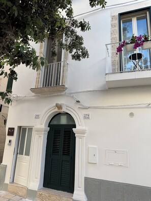 Ein Gebäude mit Balkon, einer Tür mit Glasfenster und einem Fenster mit Aussicht.