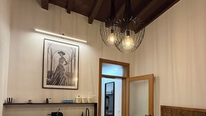 Un dormitorio con cama, mesita de noche y tocador. Hay una zona de cocina con un fregadero, armarios y encimera. Un cuadro enmarcado cuelga de la pared sobre la cama.