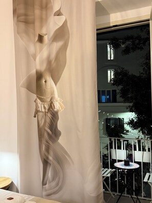 A room with a large, abstract sculpture, a balcony with chairs, and a view of a building with windows. - Angel Apartment 2 - One Bedroom Apartment, Sleeps 2 (Monopoli)