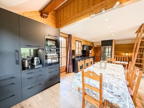 Een moderne keuken met inbouwapparatuur, een eethoek met een marmeren tafel en houten details.
