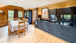 A modern kitchen with a central island, wooden dining table, and chairs. - Chalet Alpenroc - Valloire (Valloire)