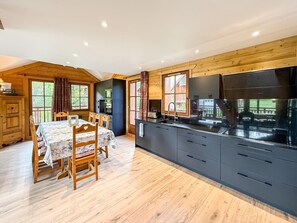 Eine moderne Küche mit Kochinsel, Esstisch aus Holz und Stühlen.