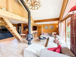 Ein Holzinnenraum mit einer Couch, einem Kamin und einer Treppe.