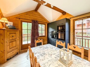 A cozy cabin-style kitchen with wooden walls, a dining table, and a large window. - Chalet Alpenroc - Valloire (Valloire)