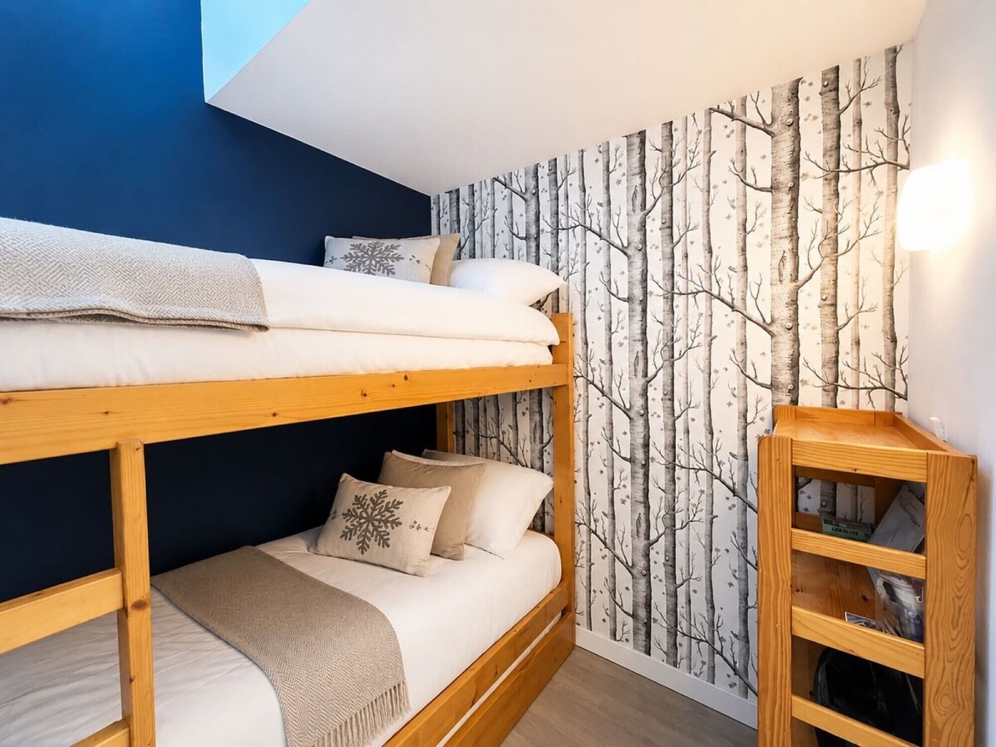 A bunk bed room with a tree wallpaper, a wooden shelf, and a skylight.