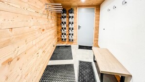 Un interior de madera con una puerta, un perchero en la pared y una mesa.