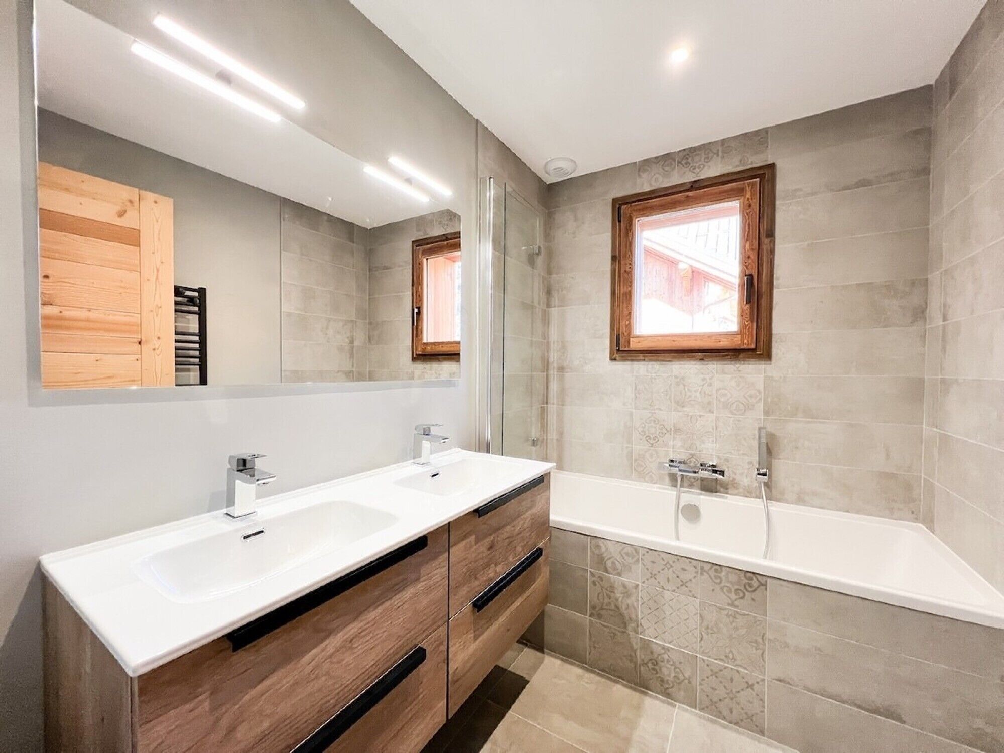 Un baño moderno con dos lavamanos, un espejo grande y una bañera.
