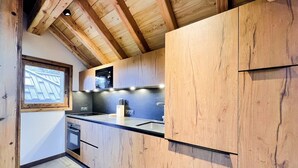 Una cocina moderna con armarios de madera, horno empotrado y ventana con vistas al tejado.