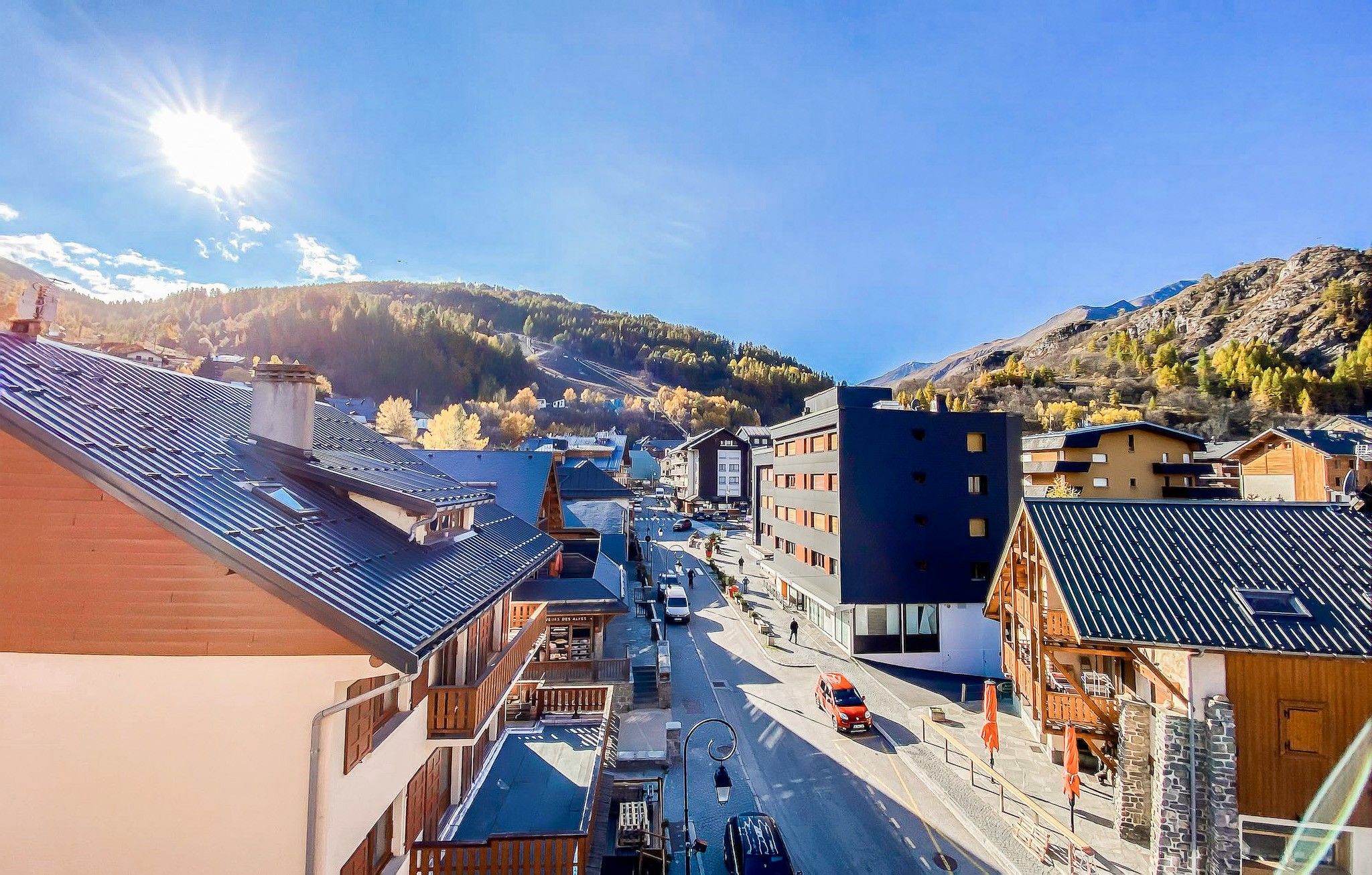 Une ville avec des bâtiments, une rue et des montagnes en arrière-plan.
