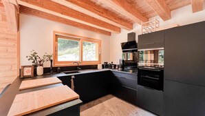 Een moderne keuken met houten balken, een groot raam en zwarte keukenkasten.