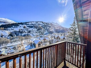 Ein Balkon mit Blick auf einen mit Schnee bedeckten Berg und ein Dorf.