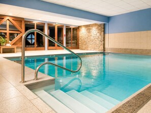 A swimming pool with a metal ladder, stone wall, and wooden doors. - Le Refuge des Cimes Valloire – Cozy Duplex at the Foot of the Slopes (Valloire)