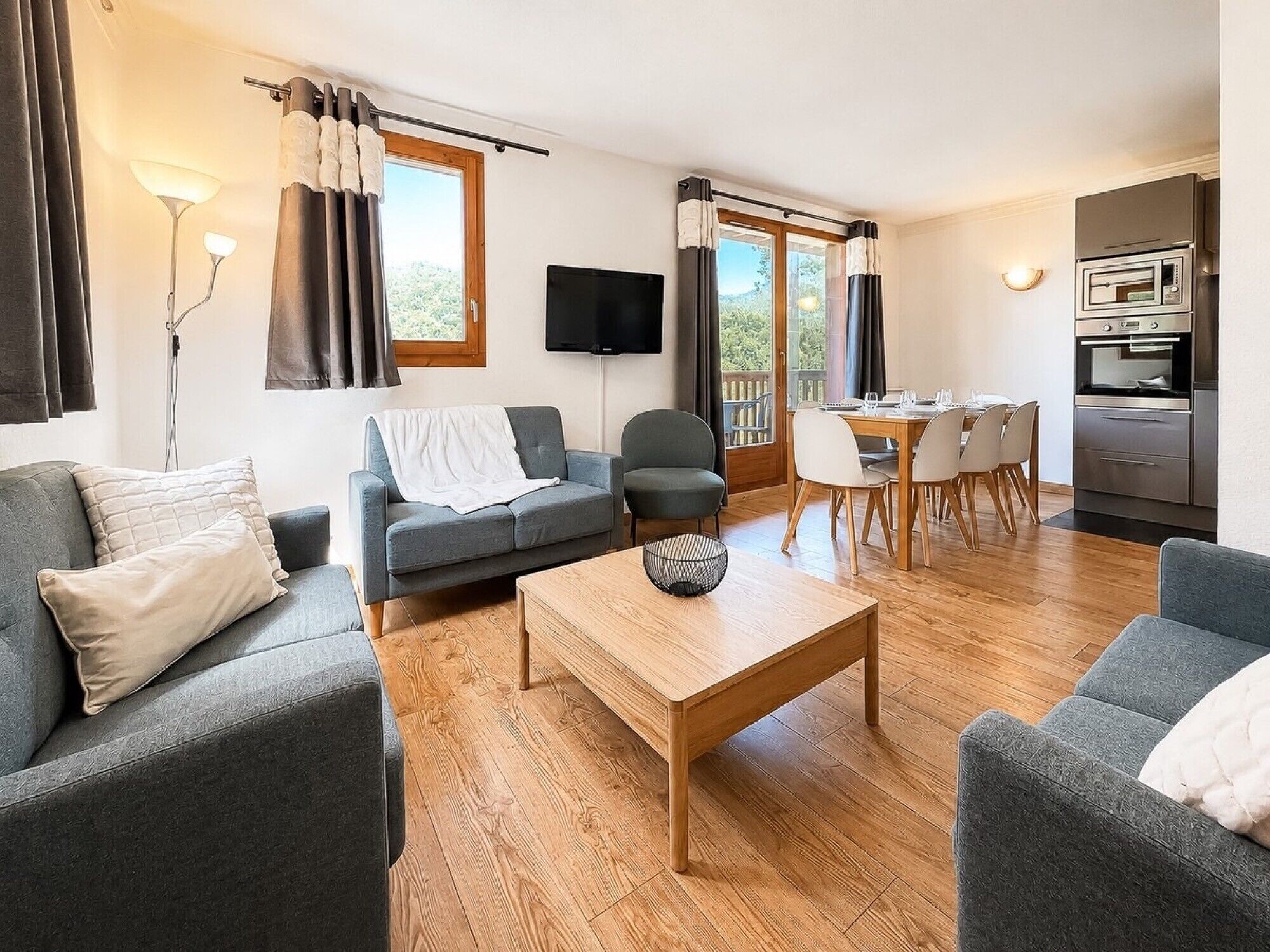 Ein modernes Wohnzimmer mit Sofa, Sessel, Couchtisch und Essbereich mit Stühlen und einem Tisch.