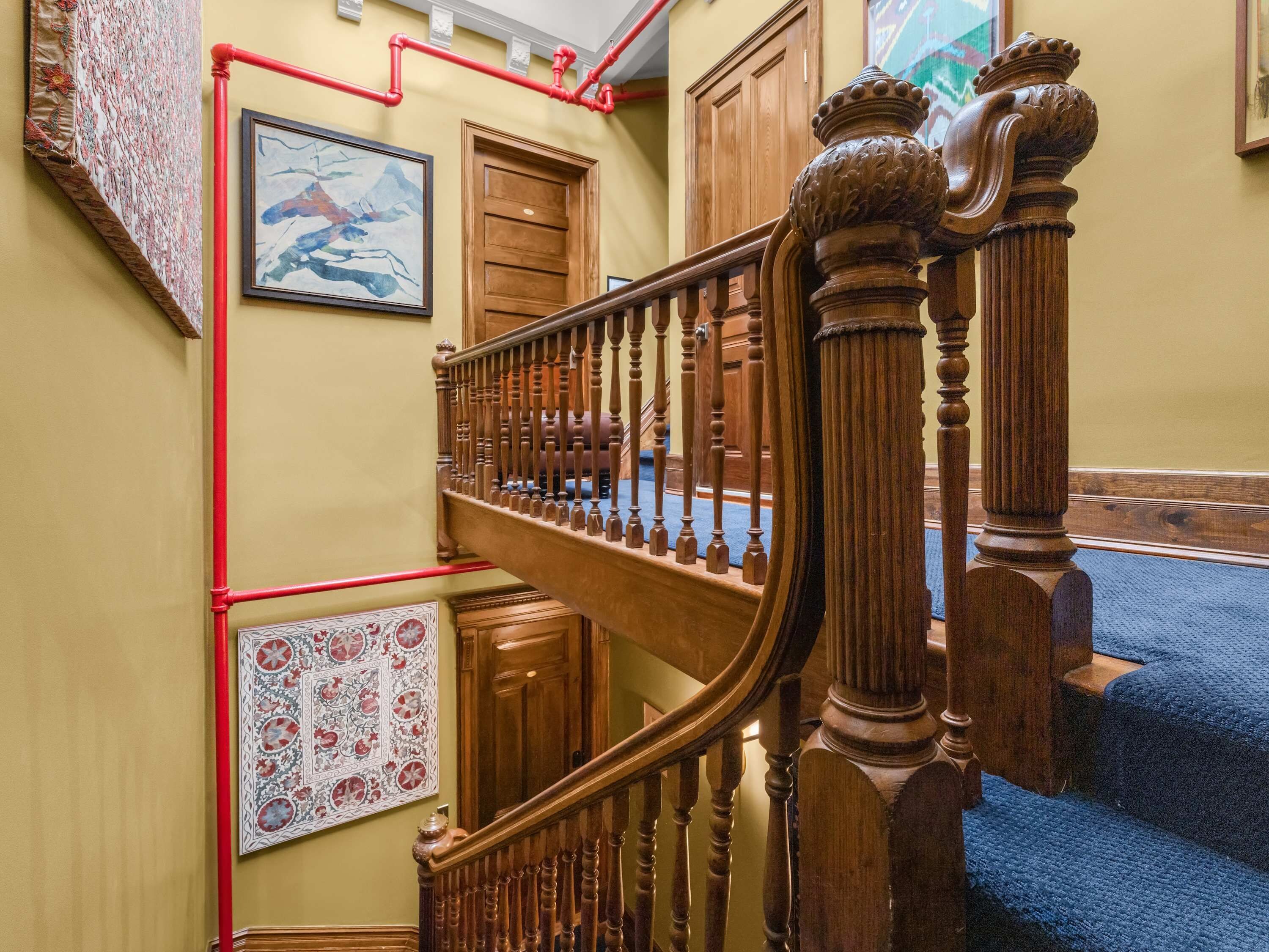 A staircase with wooden balusters and a red pipe running along the wall.