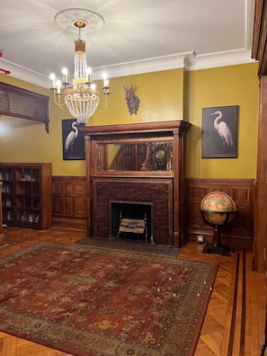 A room with a fireplace, a chandelier, a globe, and a bookshelf.