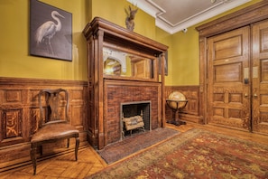A room with a wooden fireplace, a bench, a rug, and a door.