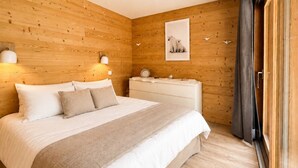 Een slaapkamer met een houten wand, een bed met wit beddengoed, een nachtkastje, een ingelijste foto en een raam met gordijnen.