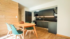 Een moderne keuken met een eethoek, houten vloer en teal-kleurige stoelen.