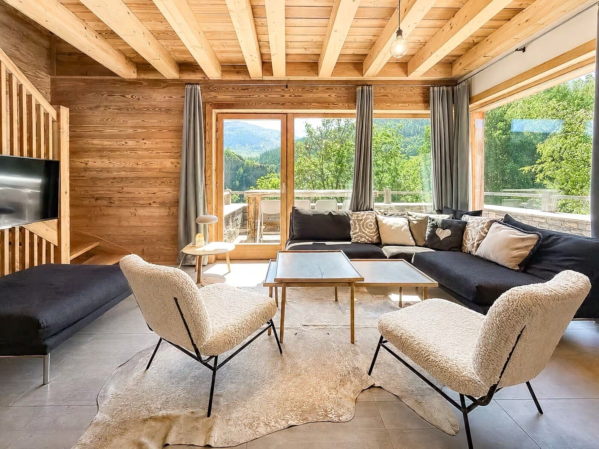 A modern living room with a sofa, two armchairs, a coffee table, and a TV.