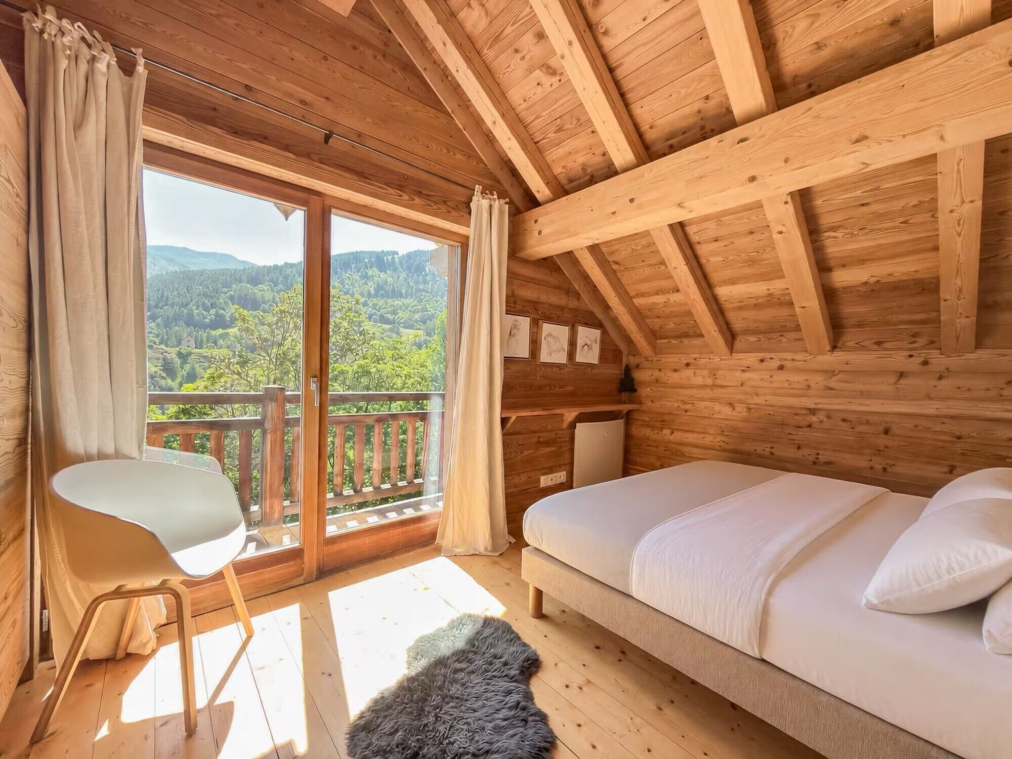 Eine Holzhütte mit Balkon, Bett und Sessel.