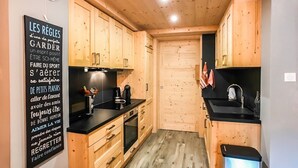 Una cocina compacta con armarios de madera, encimera negra y un lavamanos pequeño.