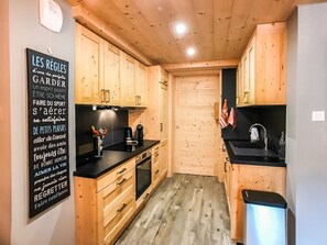 Eine kleine Küche mit Holzschränken, einer schwarzen Arbeitsplatte und einem Spülbecken.