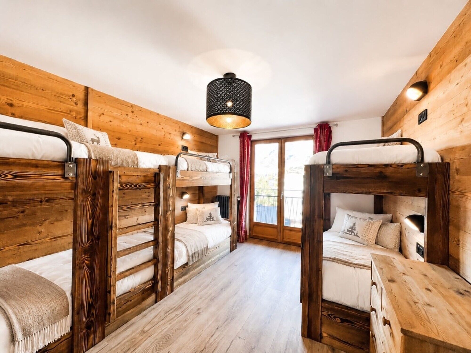 Une chambre avec des lits superposés, des murs en bois et un luminaire central.