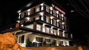 Um hotel de vários andares com varandas e uma placa com a inscrição 'LA CHAUMIERE'.