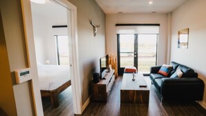 Ein modernes Hotelzimmer mit Bett, einer Couch, einem Couchtisch und einem großen Fenster.