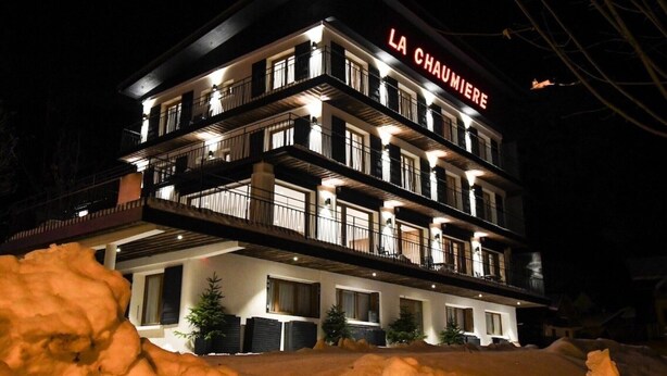 Een meerhoog hotel met balkons en een bordje met de tekst 'LA CHAUMIERE'.