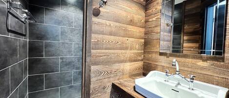 A modern bathroom with a large mirror, a white sink, and a shower area.