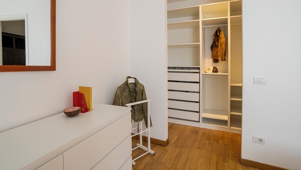 A modern room with a white dresser, a mirror, a coat rack, and a walk-in closet with shelves. - Franklin's House Como, Como, Italy (Como)