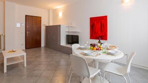 A modern kitchen with a dining table set for four, a TV, and a red abstract painting on the wall. - Franklin's House Como, Como, Italy (Como)