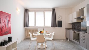 A modern kitchen with a dining area, a clock on the wall, and a radiator. - Franklin's House Como, Como, Italy (Como)