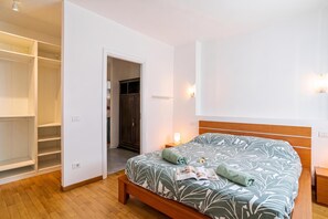 Ein Schlafzimmer mit einem Bett, einem Holzkopfteil, einem Nachttisch, einer Kommode und einem Kleiderschrank.