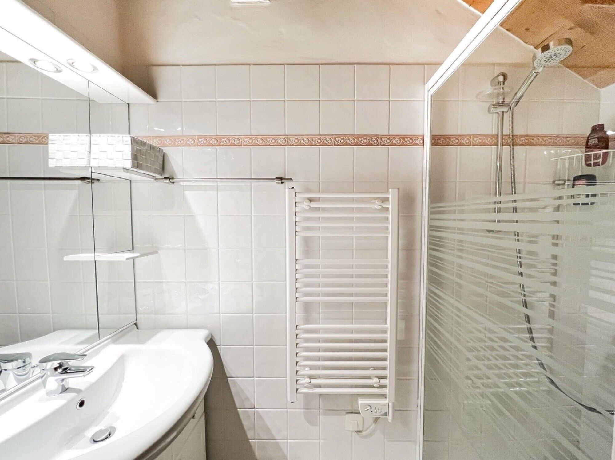 Une salle de bain moderne avec une douche à parois de verre, un lavabo blanc et un porte-serviettes.