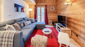 A cozy living room with a sofa, TV, and red carpet. - Apartment - Le Pti Chalet Valloire - 6 People (Valloire)