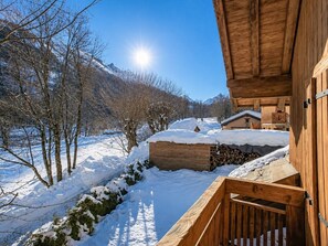 Eine Holzhütte mit schneebedecktem Dach und freiem Blick auf eine verschneite Berglandschaft.