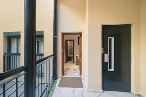 A corridor with a marble floor, a black door, and a window with a curtain. - 'Wellhome Sevilla Centro' Apartment with Wi-Fi, Parking, and Air Conditioning (Seville)