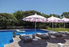 A swimming pool with lounge chairs and striped umbrellas.