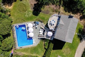 An aerial view of a property with a swimming pool, outdoor seating, and a deck. - Longtail Cottage (Nantucket)