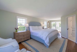 A bedroom with a bed, dresser, bedside table, and a window.