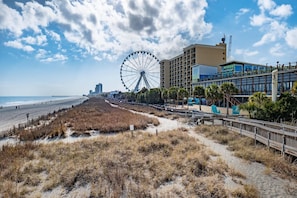 A beachside view with a Ferris wheel, a boardwalk, and a hotel with balconies overlooking the beach. - Pier & Paradise 2BR Oceanfront Suite Yachtsman 506 (Myrtle Beach)