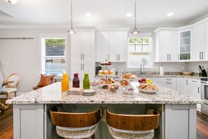 A modern kitchen with white cabinetry, a marble countertop, and a central island with seating. - Minutes to Tampa Fun | Private Pool & Spa Getaway (Tampa)